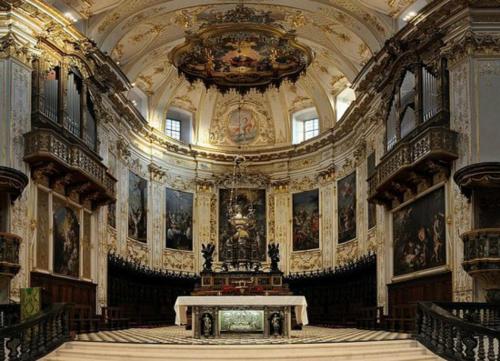 a large room with a table in a building with paintings at Donizetti Royal in Bergamo
