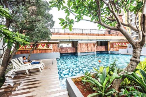 un homme assis sur une balançoire à côté d'une piscine dans l'établissement Great Western Hotel & Resort Serpong - Tangerang, à Warungmangga