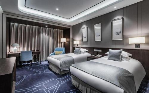 a hotel room with two beds and a desk at International Conference Hotel Nanjing in Nanjing