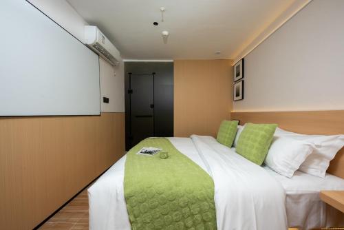 a bedroom with a large white bed with green pillows at SHI MO LI Hotel 诗茉莉酒店 in Shenzhen