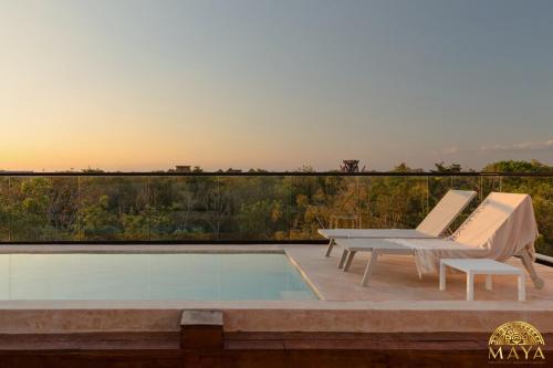 a patio with a pool and two chairs and a table at Peregrina Tulum 104A 2-Bedroom Condo in Tulum