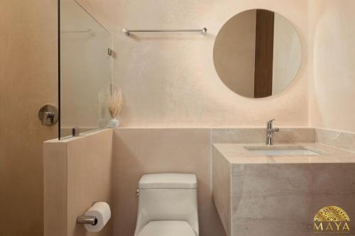 a bathroom with a sink and a toilet and a mirror at Peregrina Tulum 104A 2-Bedroom Condo in Tulum