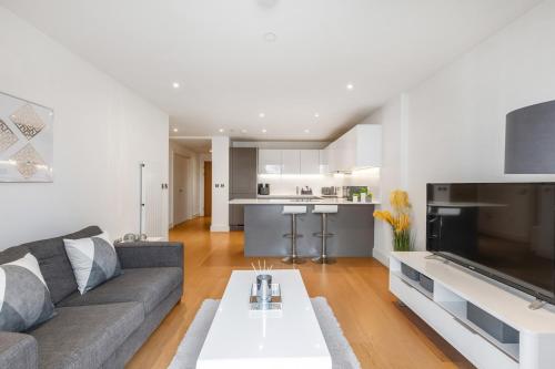 a living room with a couch and a table at Chic Luxury Apt Gym Balcony 5min to Stadium & Tube in London