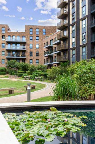 a pool of water with lilies in front of buildings at Chic Luxury Apt Gym Balcony 5min to Stadium & Tube in London