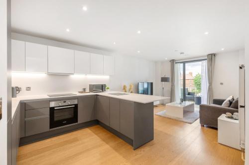 ロンドンにあるChic Luxury Apt Gym Balcony 5min to Stadium & Tubeの白いキャビネット付きのキッチン、リビングルーム