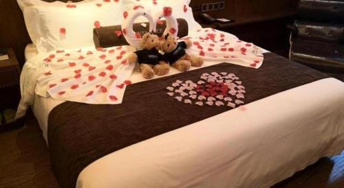 a bed with two stuffed animals sitting on it at James Joyce Coffetel Tianjin Railway Station Jinshiqiao Metro Station Branch in Tianjin
