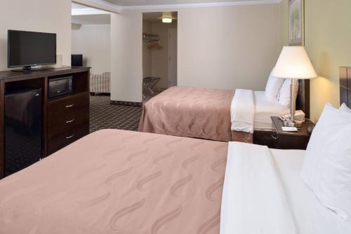 a hotel room with two beds and a flat screen tv at Quality Inn & Suites Montebello - Los Angeles in Montebello