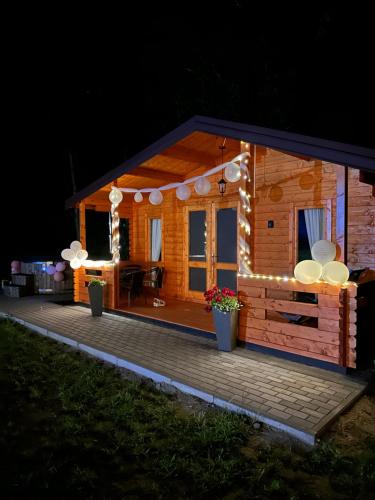 a small cabin with lights on the deck at night at Ranczo Rogowo jacuzzi sauna staw rybny in Rogowo