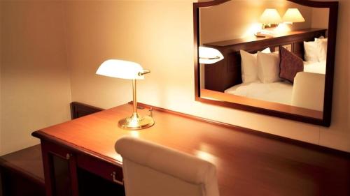 a room with a desk with a mirror and a bed at Hotel Harvest In Yonago in Yonago