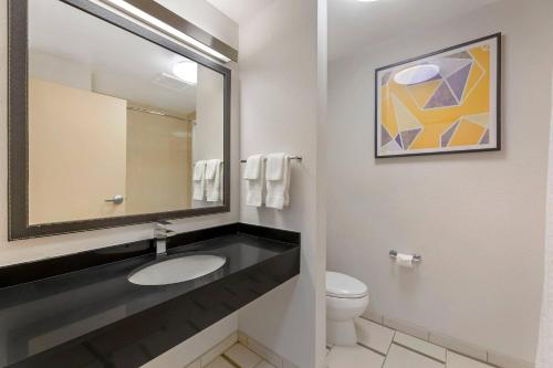 a bathroom with a sink and a mirror and a toilet at Comfort Inn & Suites Akron South in Akron
