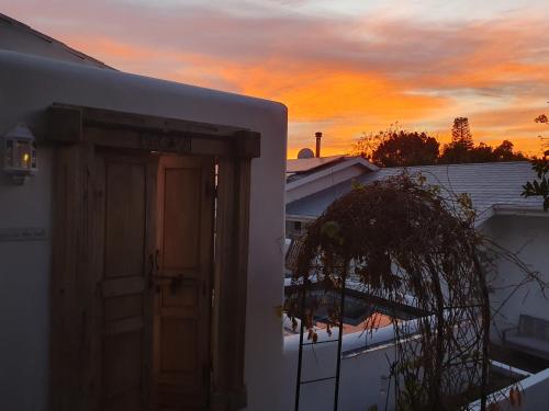 a door of a house with a sunset in the background at Long Story Guest House in Plettenberg Bay
