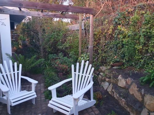 two white chairs sitting under a pergola at Long Story Guest House in Plettenberg Bay