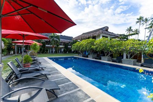 a resort pool with chairs and a red umbrella at Azure Dive Resort in Dauin