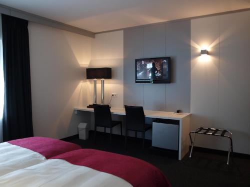 Habitación de hotel con cama, escritorio y TV. en B&B Pommerloch en Pommerloch