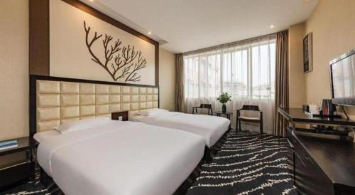 a hotel room with two beds and a television at Kunming Long Way Hotel in Kunming