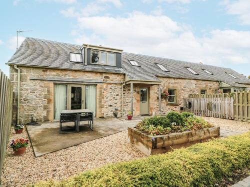 a stone house with a garden in front of it at Thorneydyke Cottage in Stirling