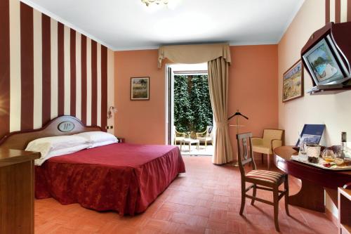 een slaapkamer met een bed, een tafel en een bureau bij Hotel Prestige in Sorrento