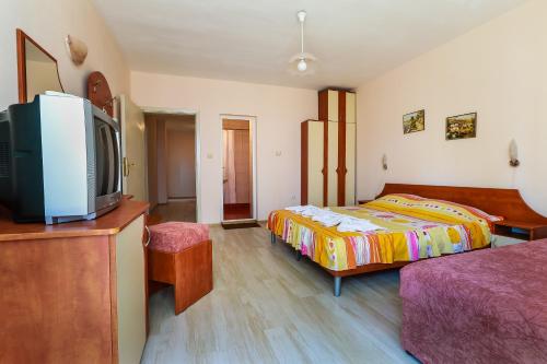 a bedroom with a bed and a tv on a dresser at Guest House ,, Ekaterina" in Nesebar