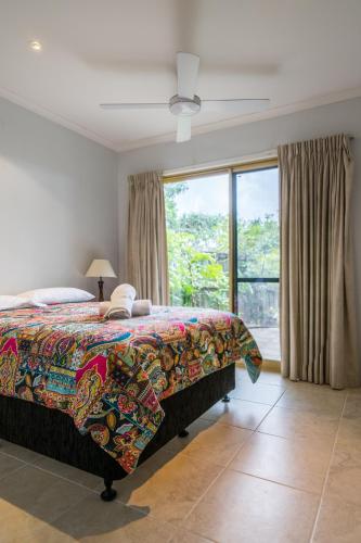 a bedroom with a bed and a large window at Pandanus Palms Holiday Resort in Point Lookout