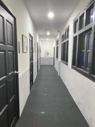 an empty hallway with a black door and windows at Quee Hotel in George Town