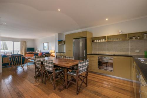 a kitchen with a wooden table and chairs at Pandanus Palms Holiday Resort in Point Lookout