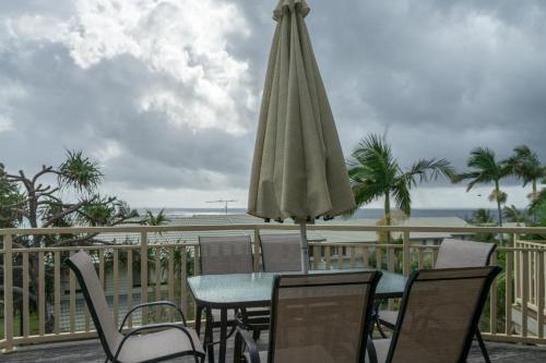 a table and chairs with an umbrella on a balcony at Pandanus Palms Holiday Resort in Point Lookout