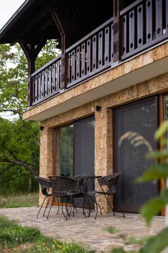 a patio with a table and a balcony on a house at Forest Heaven Retreat with jakuzz in Čačak
