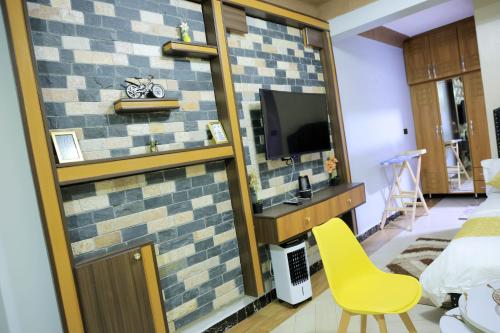 a room with a brick wall with a yellow chair at AG Home Studio - Kampala in Kampala