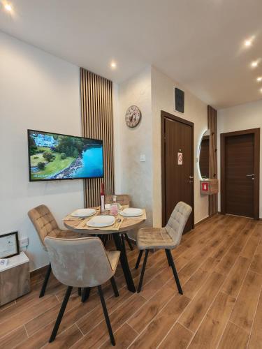 a dining room with a table and chairs and a television at POOL RESORT Vila Lena - Lux residence apartman 1 in Vrdnik