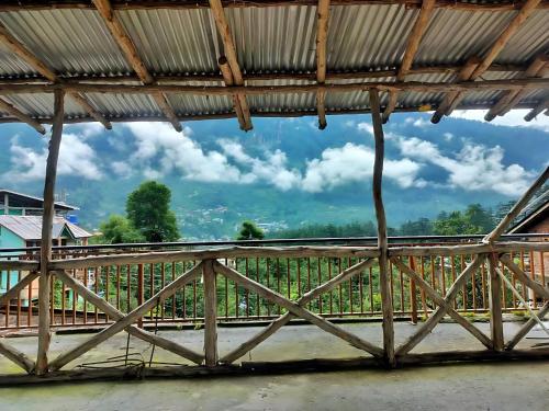 a wooden bridge with a view of a vineyard at Tonys Backpacker Hostel in Manāli