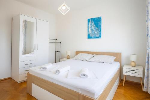 a white bedroom with a large bed with white sheets at Apartments Nikola in Gradac