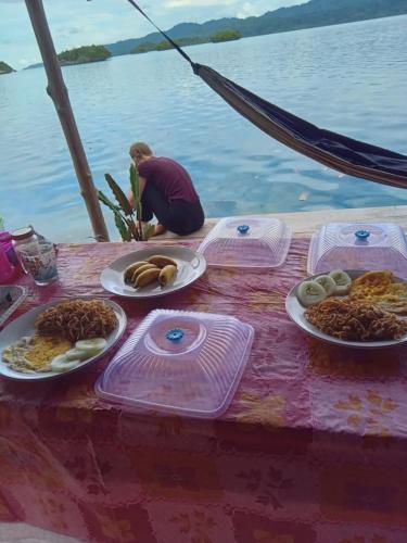 a table with plates of food on top of the water at "Shady Sea Raja Ampat" in Besir