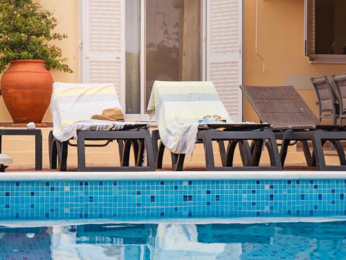 two chairs and a table next to a swimming pool at Beach villa Casa de Amanhã 450 mts to the beach with beautiful garden and heated saltwater pool in Albufeira