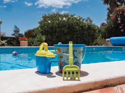 two plastic chairs and a cup next to a pool at Beach villa Casa de Amanhã 450 mts to the beach with beautiful garden and heated saltwater pool in Albufeira