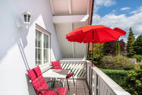 a patio with a table and chairs and a red umbrella at Sandhasen in Rimlos