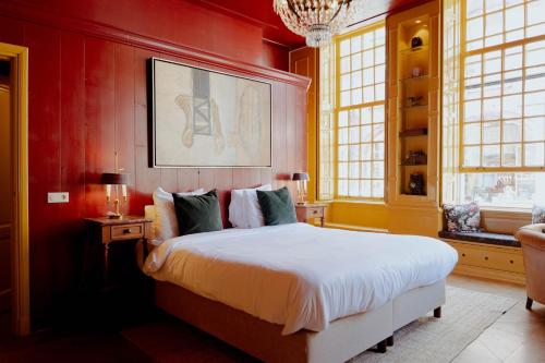 a bedroom with a bed with red walls and a chandelier at Hotel Beijers in Utrecht