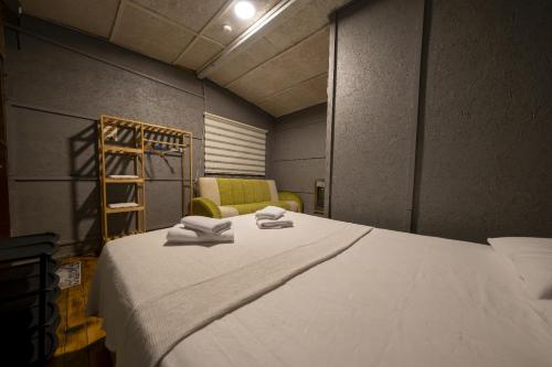 a bedroom with a large white bed and a chair at İda Tahtalıköy Bungalov in Edremit