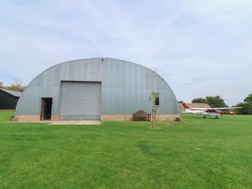 a large hangar with a door in a field with an airplane at Oak Tree in Woodbridge
