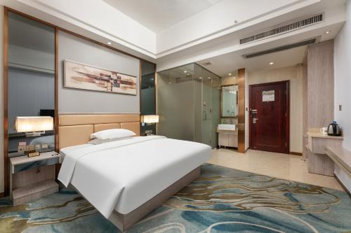 a bedroom with a large white bed and a bathroom at Penguin Airport international hotel & included free shuttle bus in Yinghai