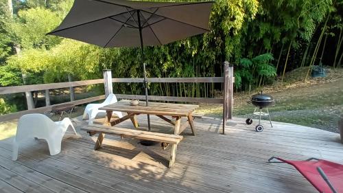 a picnic table and a grill with an umbrella on a deck at Domaine Le Mayne in Chabrignac