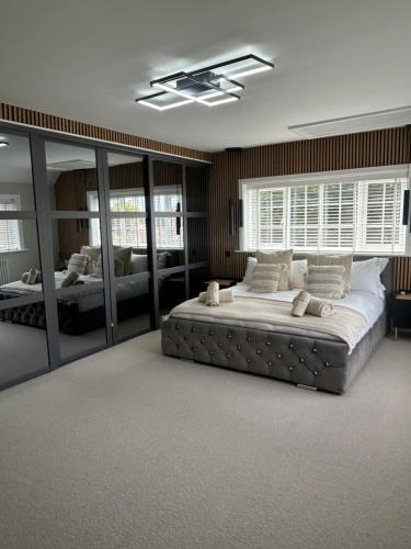 a large bedroom with a large bed and mirrors at Stranraer House and pool in Selsey