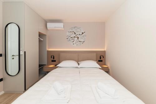 ein Schlafzimmer mit einem großen weißen Bett und einem Spiegel in der Unterkunft Luxury Suites Zaton by Belmont Realty in Zaton
