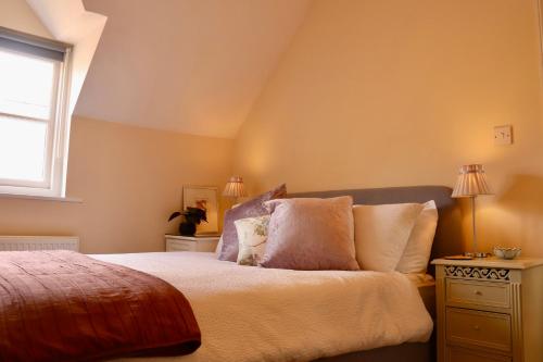 a bedroom with a bed with pillows and a window at Templar Mews, town centre 2 bedroom, 2 bathroom house in Cirencester