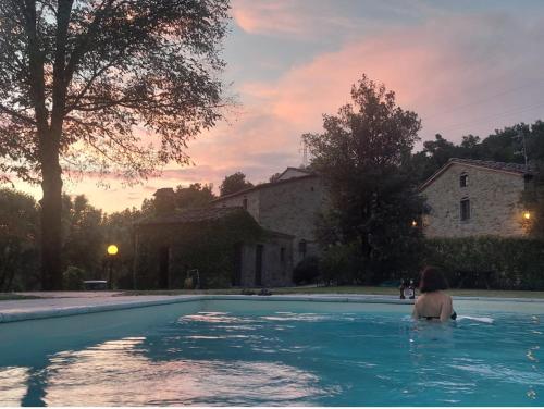 a woman is sitting in a swimming pool at Romantic cozy house 15 min Arezzo piscina&bosco in Falciano
