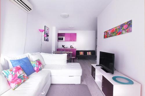 a white living room with a white couch and a tv at PoolView Elite Apartment in RoseGardenComplex with BigPool and Parking in Balchik
