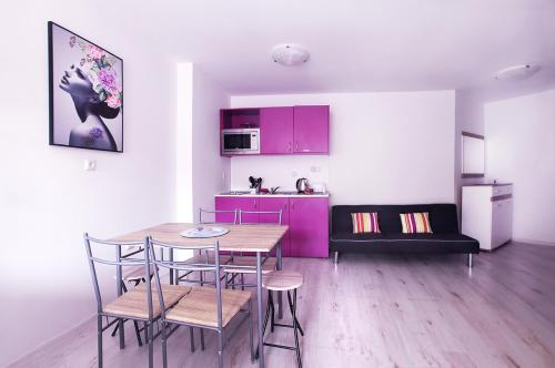 a kitchen with a table and chairs and purple cabinets at PoolView Elite Apartment in RoseGardenComplex with BigPool and Parking in Balchik