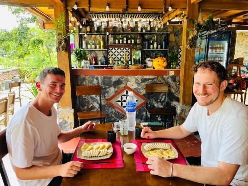 two men sitting at a table in a restaurant at Local Homestay Du Gia in Ha Giang
