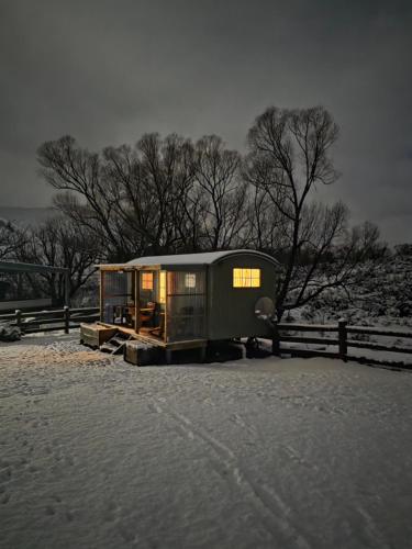 a house sitting in the snow next to a fence at Shepherds Hut Gateway to Tekapo and the MacKenzie District in Burkes Pass
