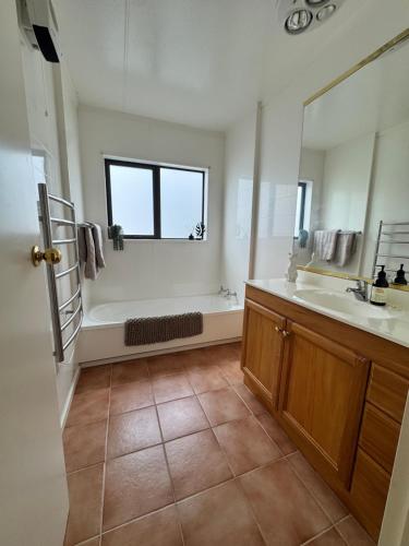 a bathroom with a tub and a sink and a mirror at River Stone Retreat in Turangi