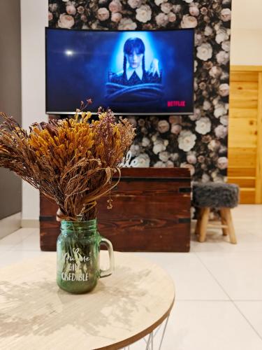 a mason jar with dried flowers sitting on a table with a tv at Cozy Retreat in San Ġwann